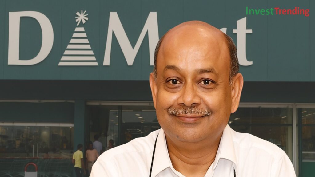 Radhakishan Damani, dressed in a white shirt with a warm smile, is seen in front of a DMart store entrance featuring the recognizable DMart logo. The InvestTrending brand logo is visible in the top-right corner.
